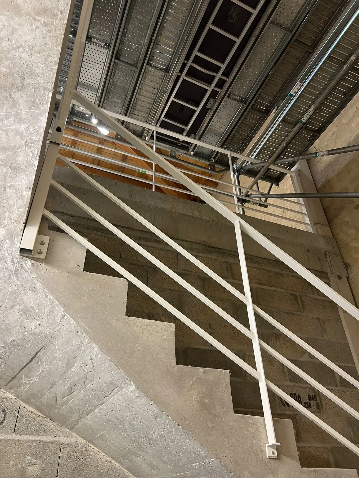 Escalier en béton avec garde-corps métallique dans un chantier de plâtrerie à Bordeaux